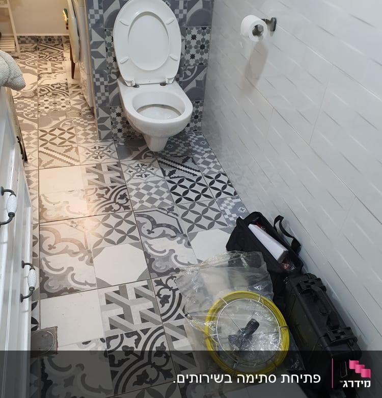 כלי עבודה של אינסטלטור ליד אסלה בחדר אמבטיה